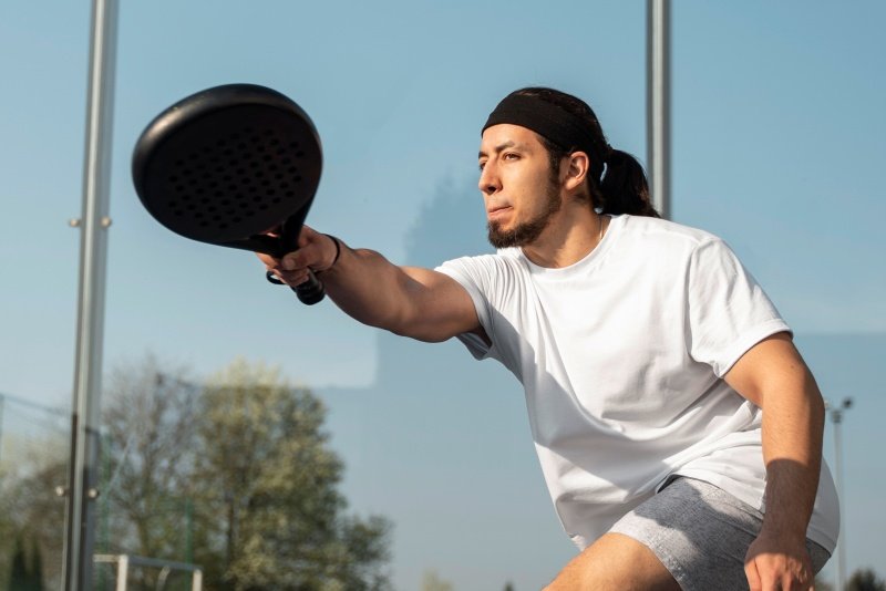 Man playing padel with black racket Man playing padel tennis with a black racket in outdoor court