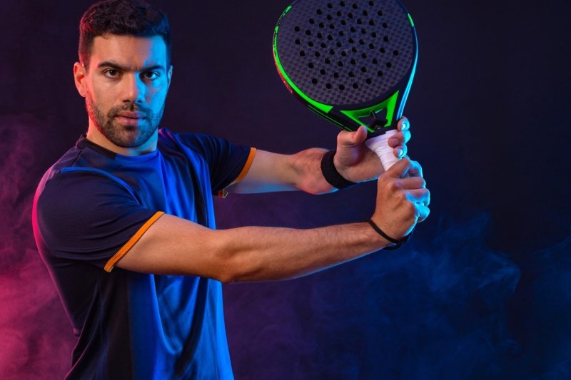 Padel action shot with paddle Padel player in action with green paddle and colored smoke