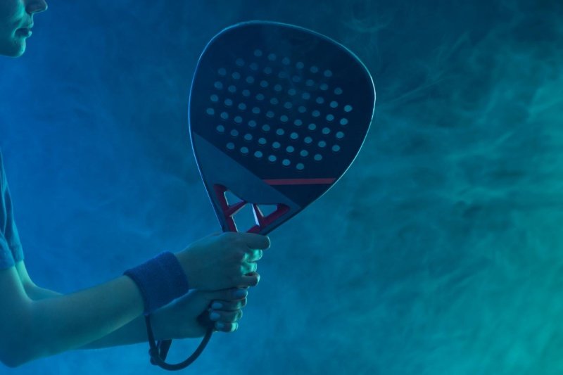 Padel action shot Padel player holding paddle with a blue fog background