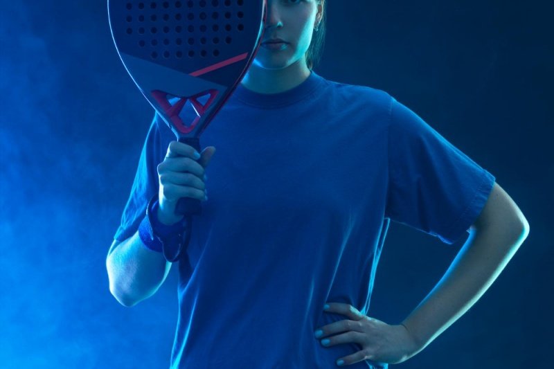 Padel player portrait Padel player with paddle, blue fog background, confident stance