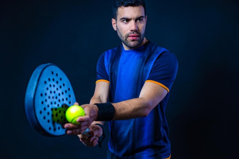 Padel player with ball Padel player preparing to strike ball, blue background