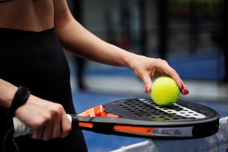 Padel racket and tennis ball close-up A close-up of a woman holding a padel racket and a tennis ball