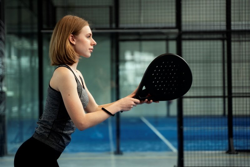 Woman playing with black padel racket A woman holding a black padel racket in action, ready to play