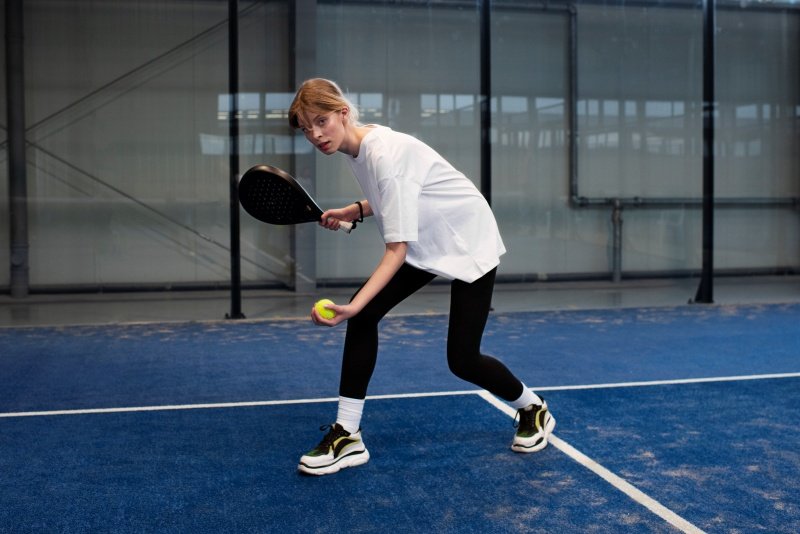 Woman preparing to serve in padel tennis, holding racket and ball
