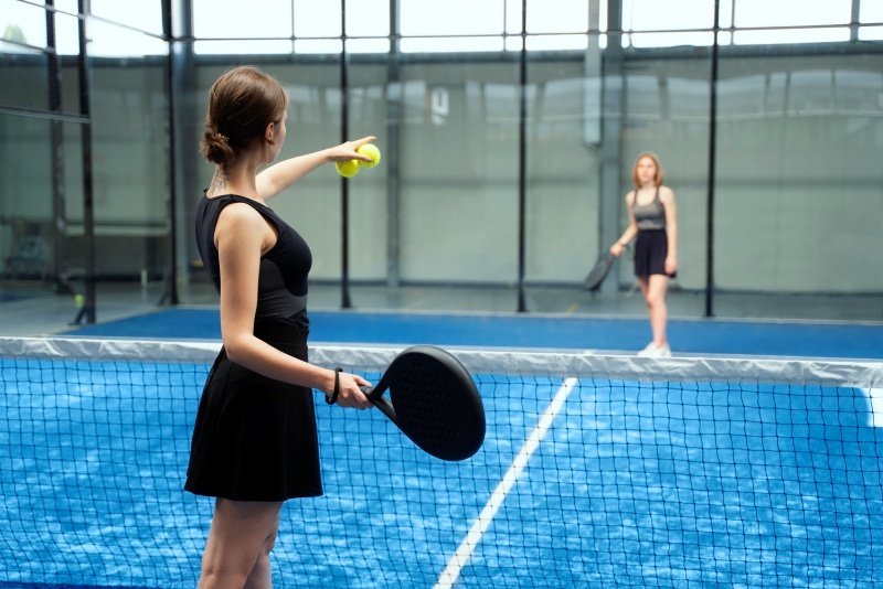Women preparing to serve in padel tennis Two women playing padel tennis, one preparing to serve