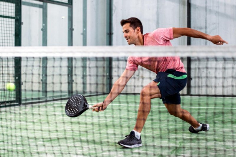padel-low-shot Padel player making a low shot, indoor court, red shirt