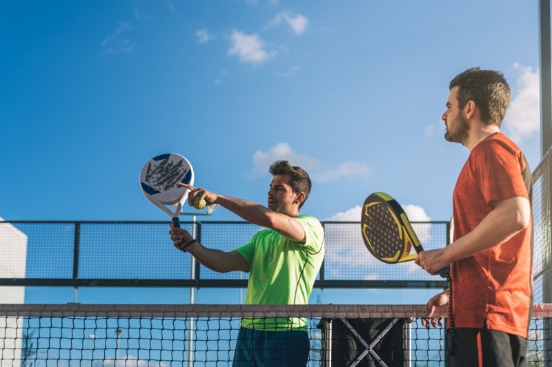 padel-match-outdoor-play two men playing padel on court, one pointing