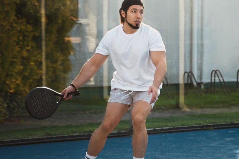 man in action on padel court with racket