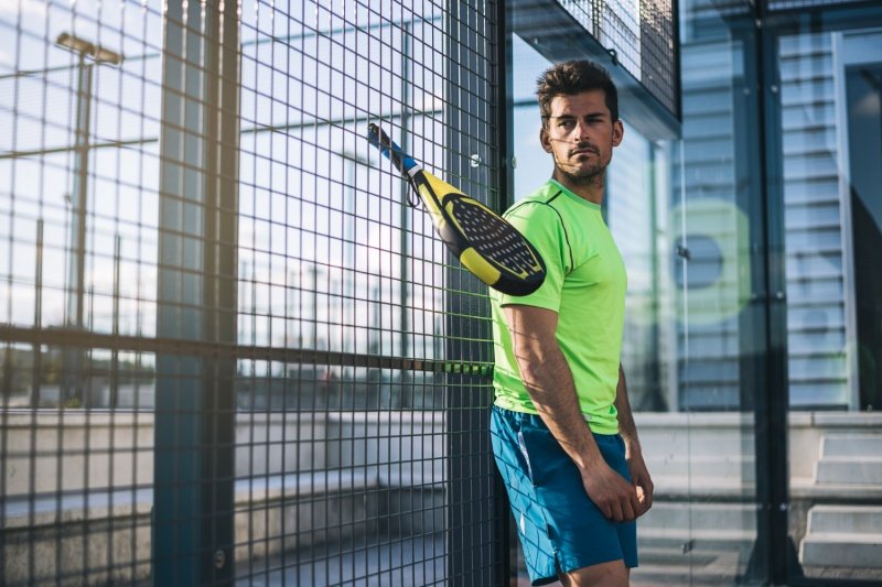 padel-player-racket-court-action man with padel racket near fence