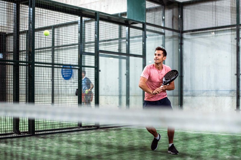 padel-player-return Padel player preparing to return shot, indoor court, red shirt