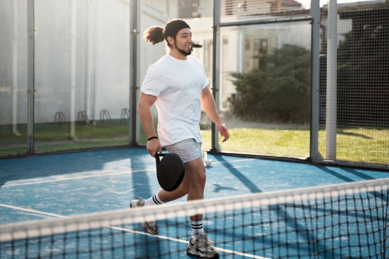 man running on padel court with racket