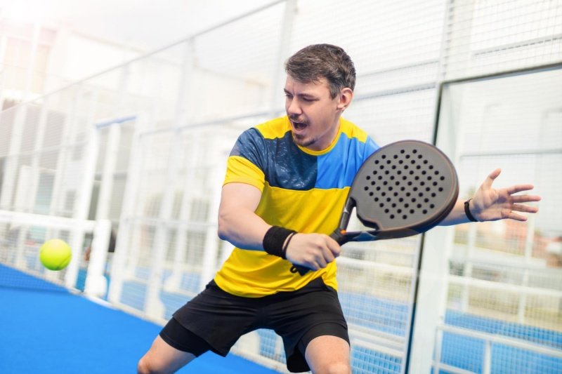 man hitting padel ball in action on court