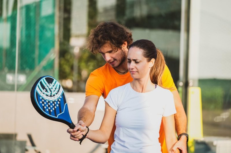 man guiding woman in padel game with racket