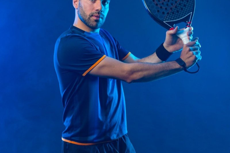 Backhand Padel Pose Male padel player in blue shirt preparing for backhand shot