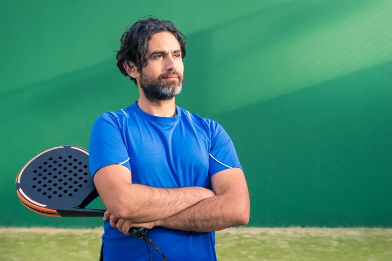 Confident padel player in blue shirt holding racket