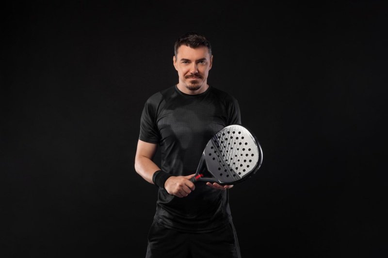 Confident Padel Player Confident male padel player holding racket against black background