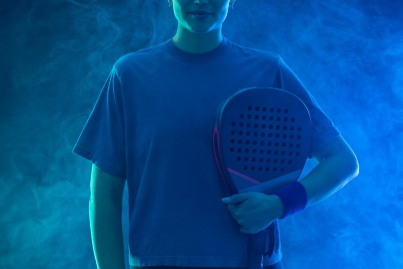Confident padel player Padel player holding a racket under blue dramatic lighting