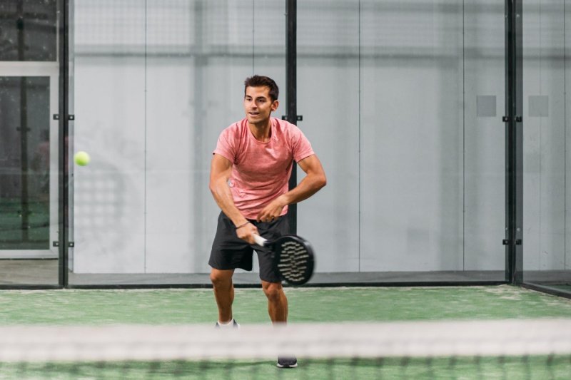 Focused athlete on padel court Padel player preparing to return the ball