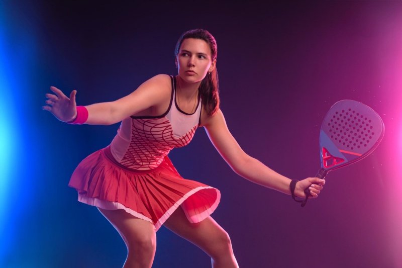 Focused padel player in action Female padel player in red outfit preparing to strike