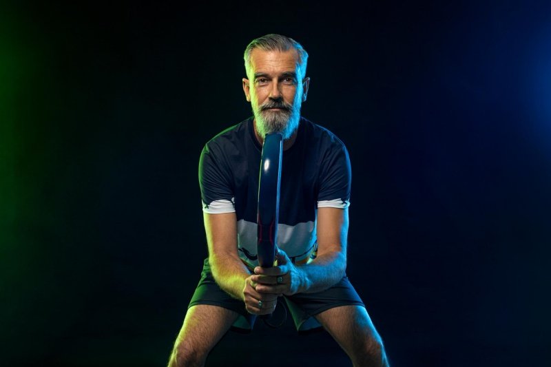 Focused padel player preparing Senior padel player in ready position with racket