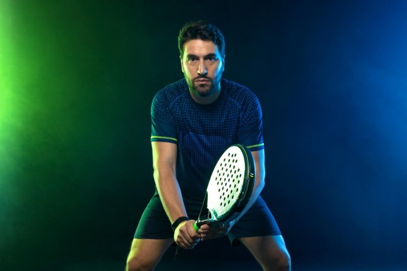 Focused padel stance Padel player in a ready position under vibrant lighting