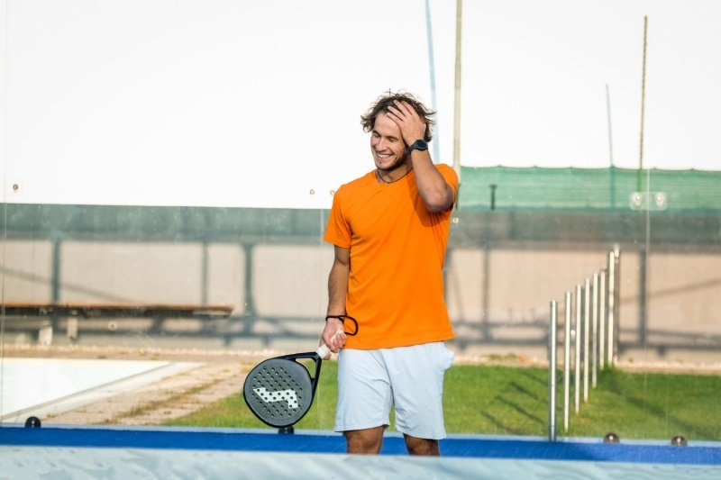 Happy padel moment Smiling padel player holding a racket on the court