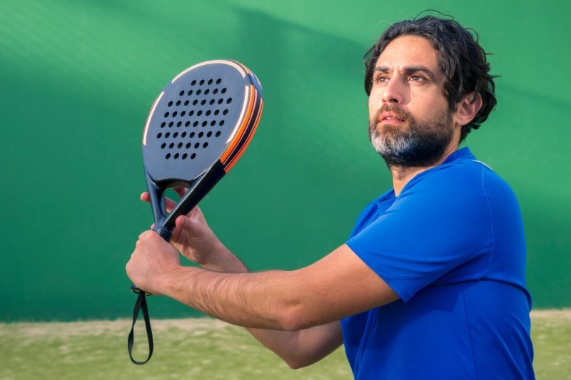 Focused padel player preparing to swing racket outdoors
