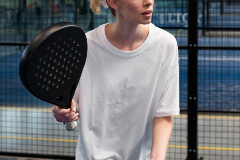 Padel Player Ready Indoors Focused padel player holding black racket indoors