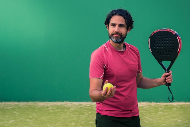 Padel player in red shirt preparing to serve