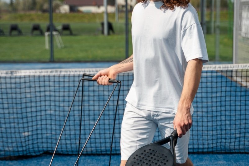 Padel court maintenance Padel player cleaning the court with a drag brush