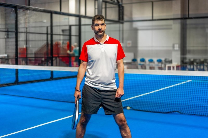 Padel court readiness Padel player standing on a blue indoor court