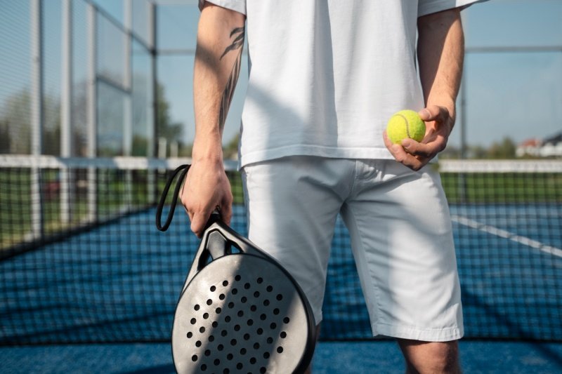 Padel equipment close-up Padel player holding racket and ball on blue court