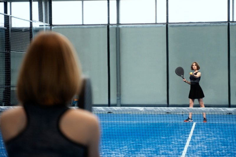 Padel match in action Two female padel players facing off on a blue court during a match