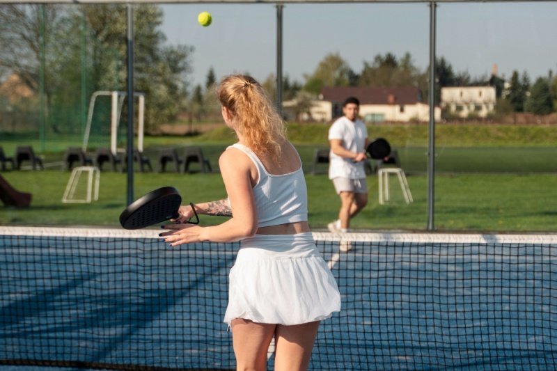 Padel players in white rallying on an outdoor court