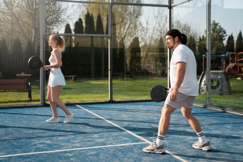 Padel doubles team in action on a blue outdoor court