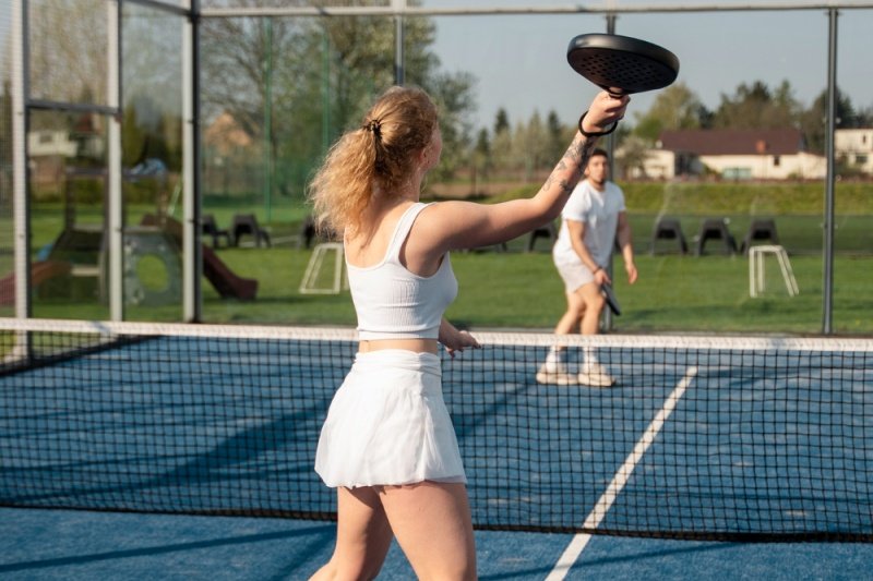 Female padel player in white hitting a shot at the net