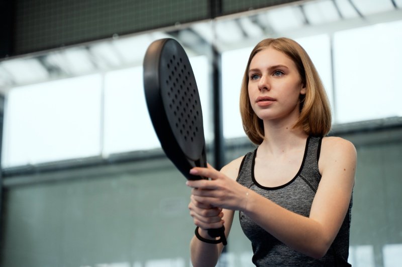 Padel player in action Focused female padel player holding a black racket, preparing for a shot