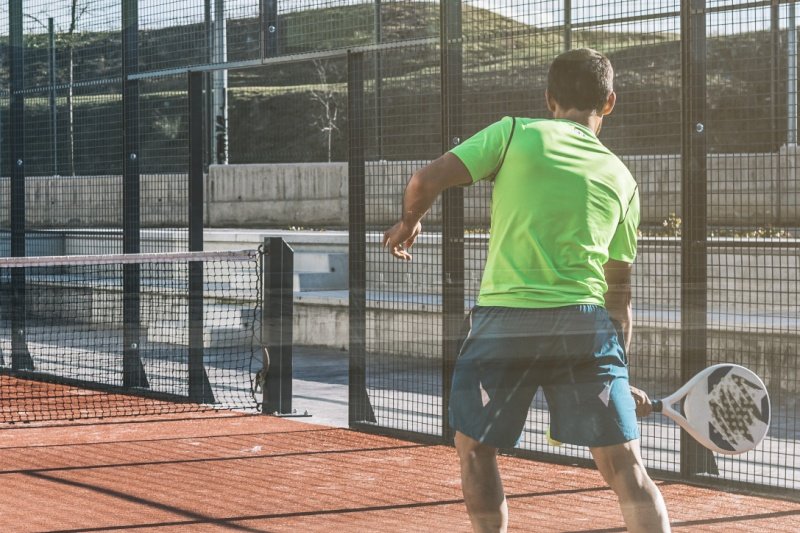 Padel player in action Male padel player preparing to hit the ball on court
