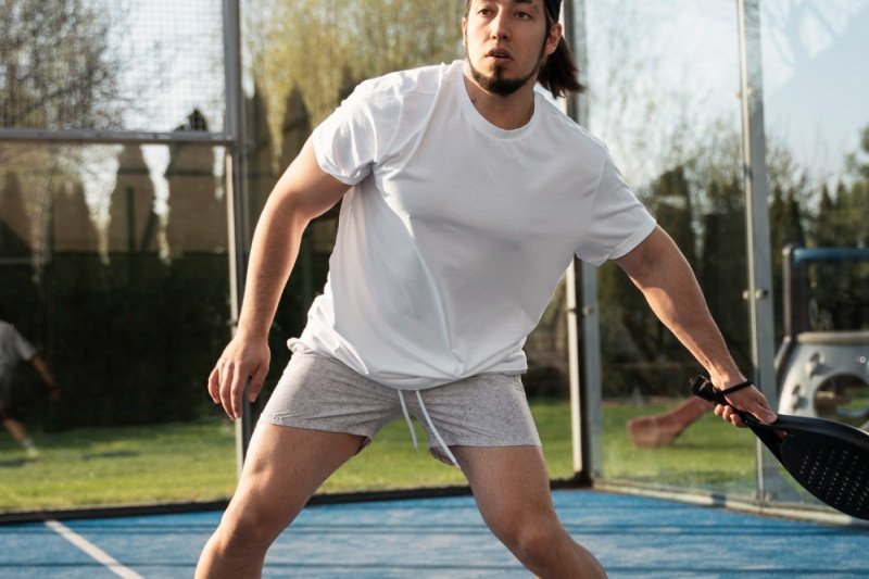 Focused padel player in white outfit preparing to hit the ball