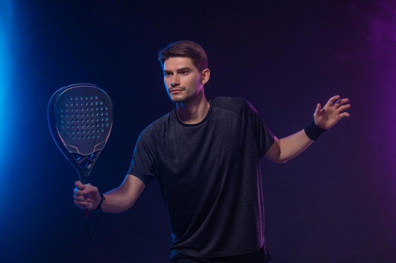 Padel player in focus Padel player ready for action under dramatic lighting