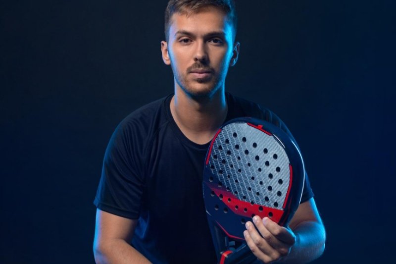 Padel player portrait Male padel player holding a red and black racket