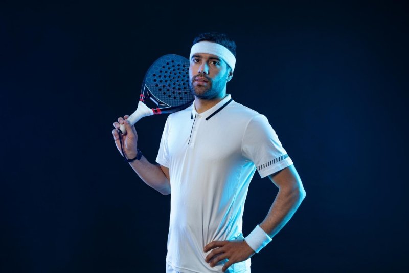 Padel player posing with racket Confident padel player holding racket on shoulder