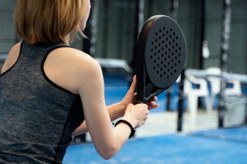 Padel player ready to hit Female padel player gripping a black racket, preparing for a shot