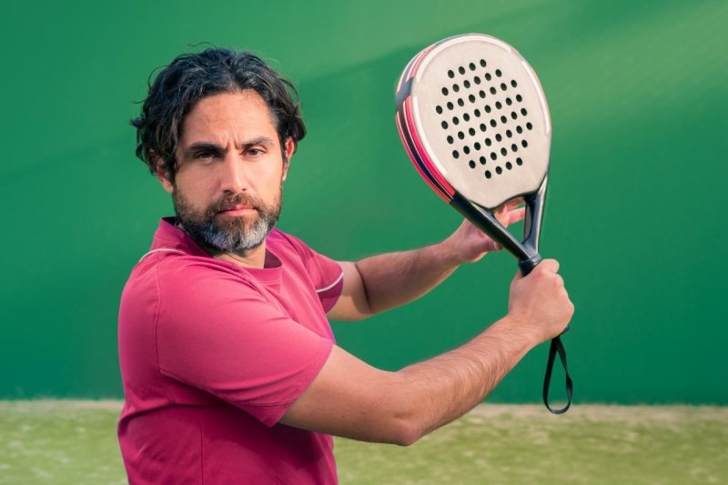 Padel player ready to swing Focused padel player preparing to hit the ball on a green court