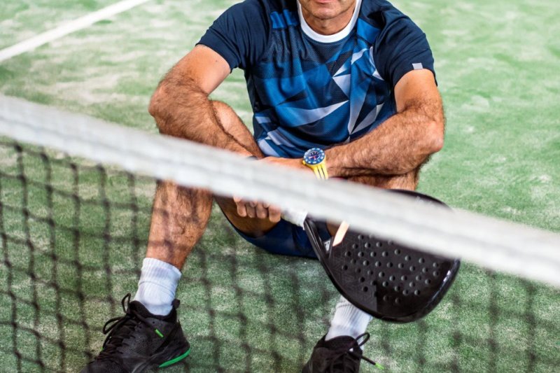 Padel player resting Padel player sitting on the court holding racket