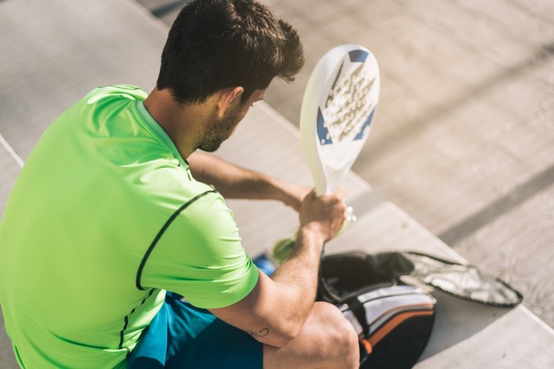 Padel player resting Padel player sitting on steps holding racket