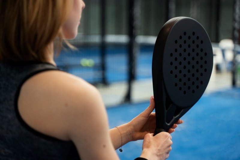 Padel racket close-up Close-up of a female padel player holding a black racket on a blue court