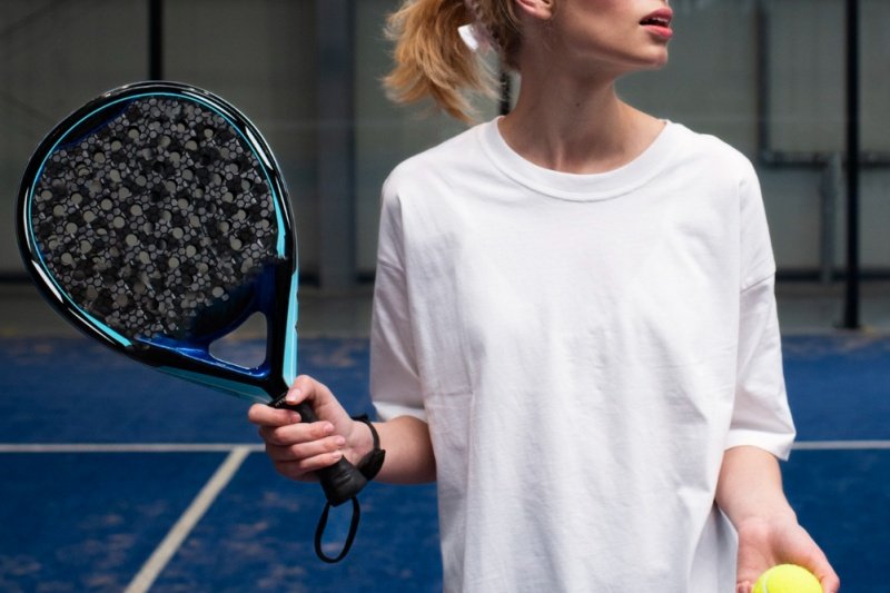 Padel player holding a blue and black racket on a blue court