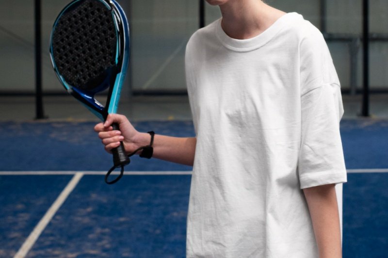 Close-up of female padel player holding a blue and black racket on a court