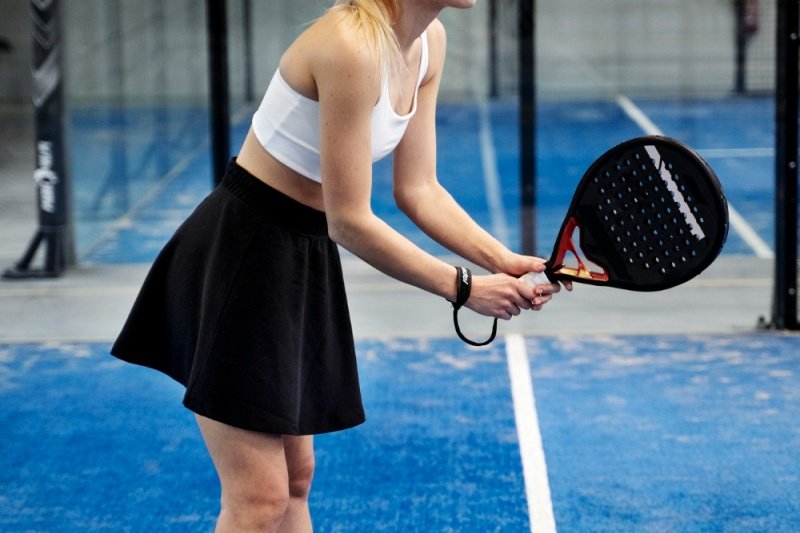 Padel serve stance Female padel player preparing to serve on blue court
